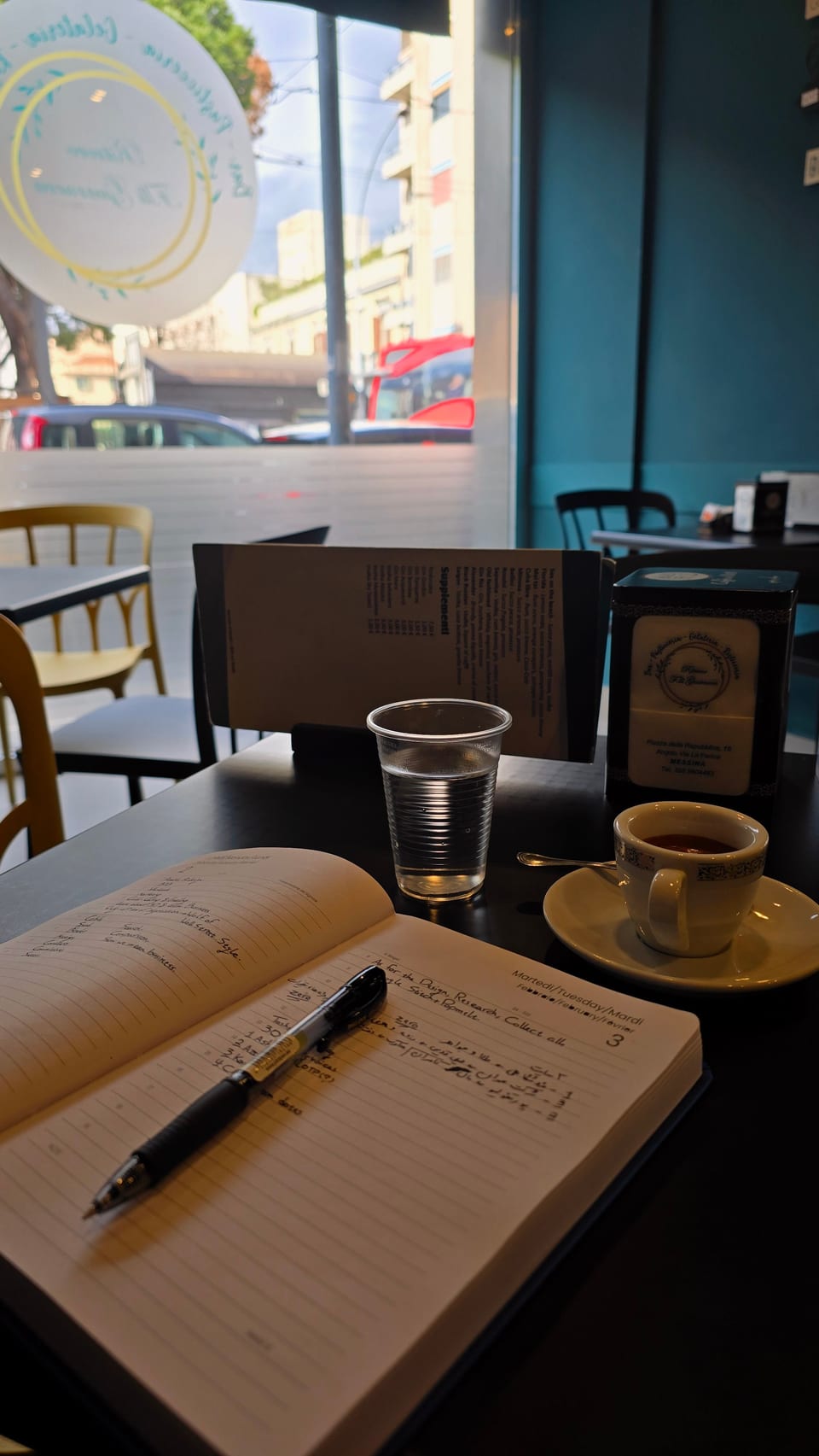 A notebook and an espresso on a café table in Messina