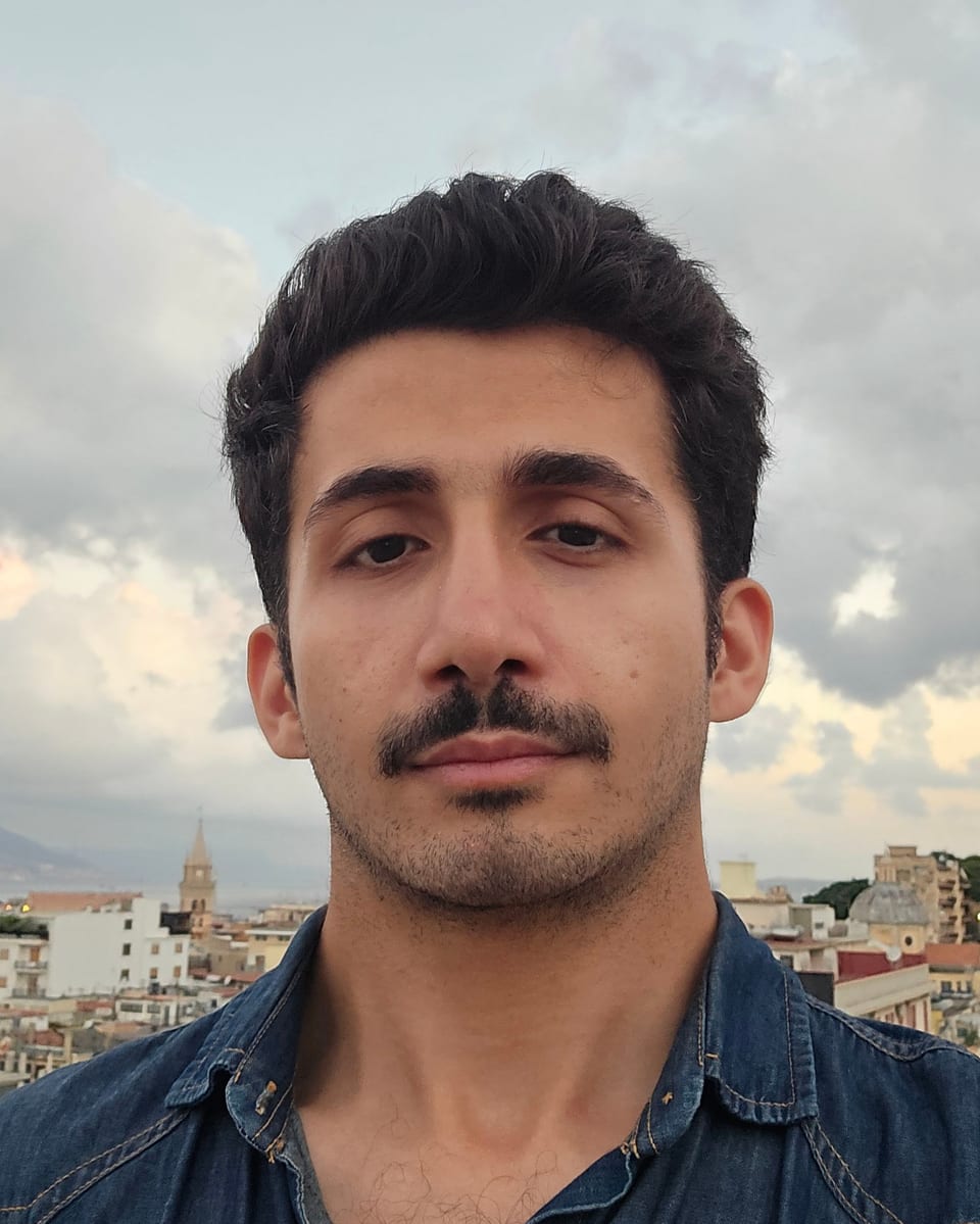Matin Azad Milani on a rooftop in Messina, the strait behind him